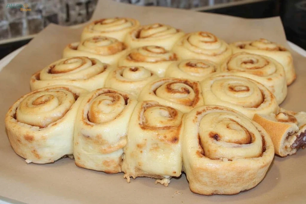 A single cinnamon roll covered in melting icing on a white plate, showcasing its tender texture.