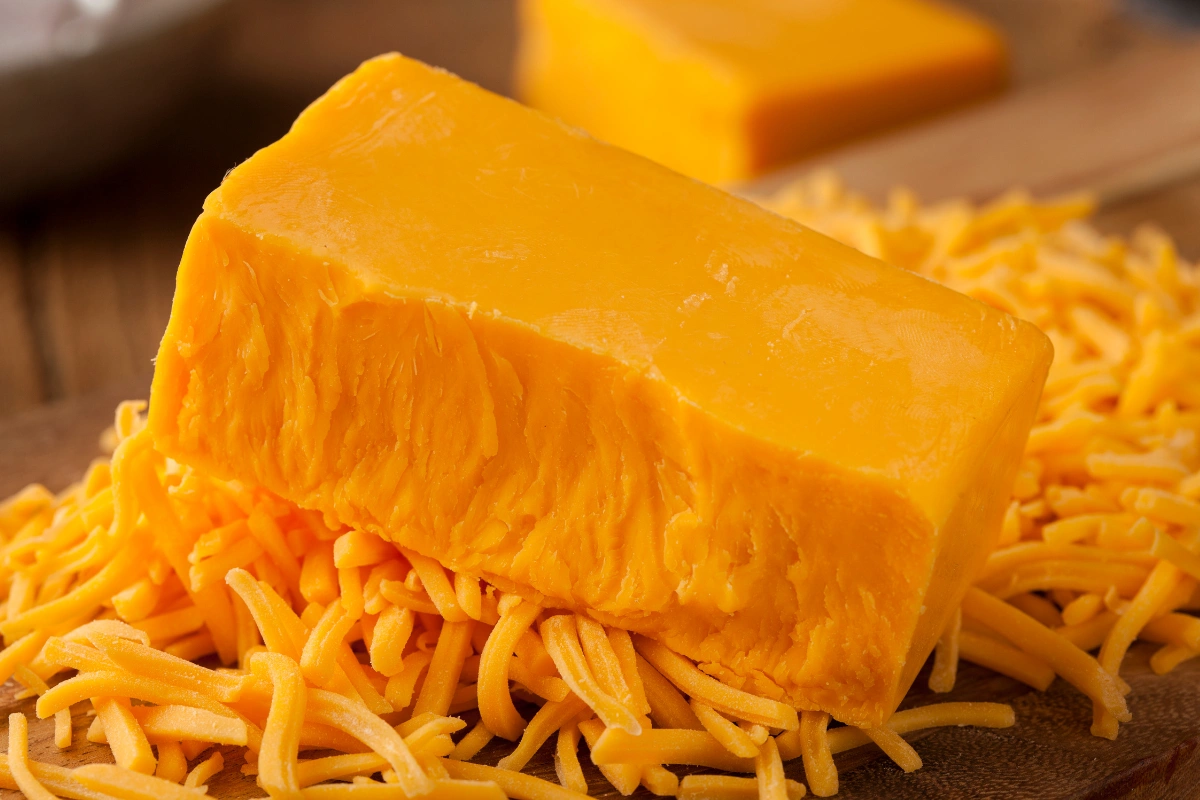 A wheel of Bellavitano cheese with a cheese knife on a wooden board.